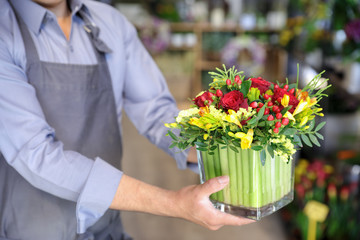 Beautiful bouquet of red roses, yellow freesia and other flowers in the male florist hands.