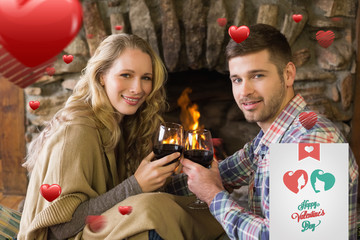 Romantic couple toasting wineglasses in front of lit fireplace against cute valentines message