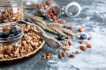 Muesli or granola in a bowl with a spoon, blueberries and nuts. Healthy breakfast
