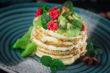 Delicious cake with fruit and mint decoration on black background