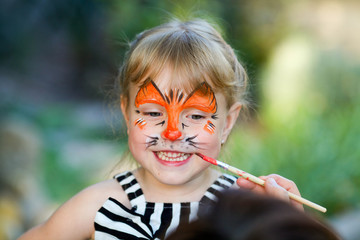 Adorable girl getting her face painted