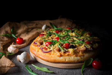 Pizza with chicken, arugula, cheese and onions on wooden rustic table