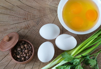 Composition from foods of egg, yolk, pepper, greenery, on a wooden background. Kind from above.