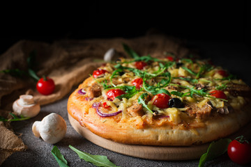 Pizza with chicken, arugula, cheese and onions on wooden rustic table