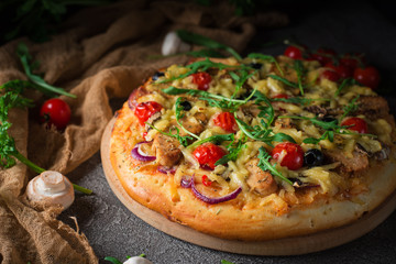 Pizza with chicken, arugula, cheese and onions on wooden rustic table