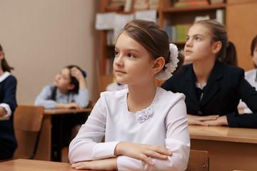 Smiling elderly teacher near the chalkboard asking student