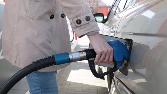 A gas station, a woman's hand holds a gasoline pistol.