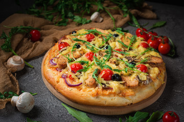Pizza with chicken, arugula, cheese and onions on wooden rustic table. Top view