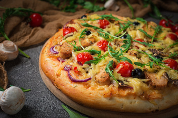 Pizza with chicken, arugula, cheese and onions on wooden rustic table. Top view