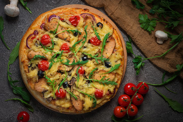Pizza with chicken, arugula, cheese and onions on wooden rustic table. Top view
