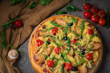 Pizza with chicken, arugula, cheese and onions on wooden rustic table. Top view