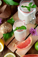 Coconut cocktail in glass jars surrounded by lime, lemon and ice cubes. Top view