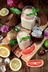 Coconut cocktail in glass jars surrounded by lime, lemon and ice cubes. Top view