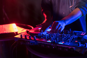 Music Concepts. DJ is rhythm music with Controller and mixer. DJ is playing the song at the party. Young are adjusting the music with the controller. The fun of music and light colors.
