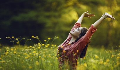 Happy young girl smiling with arms raised outdoor.