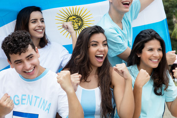 Group of cheering soccer fans from Argentina with argentinian flag - obrazy, fototapety, plakaty