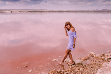 pink lake. Lake Torrevieja in Spain is pink. A girl is walking along the coast. Girl tourist in a summer dress on a background of a beautiful sea landscape 
