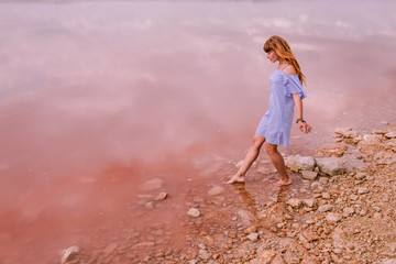 pink lake. Lake Torrevieja in Spain is pink. A girl is walking along the coast. Girl tourist in a summer dress on a background of a beautiful sea landscape 
