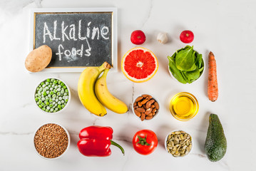 Healthy food background, trendy Alkaline diet products - fruits, vegetables, cereals, nuts. oils, white marble background above copy space