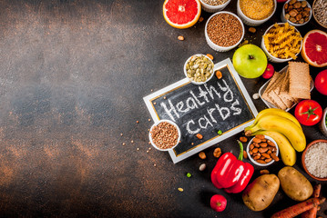 Diet food background concept, healthy carbohydrates (carbs) products - fruits, vegetables, cereals, nuts, beans, dark blue concrete background top view copy space