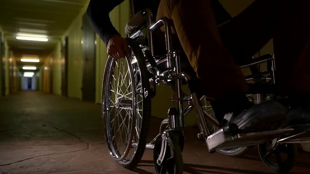 close up shot of a wheelchair, a man twists the wheels in order to move around the hospital hall