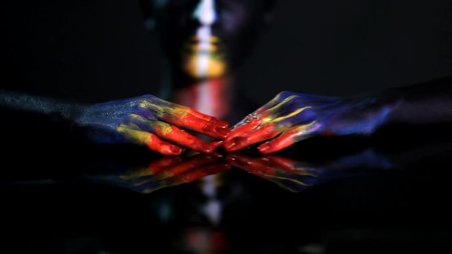 Hands of a dark-skinned glowing girl with color make-up