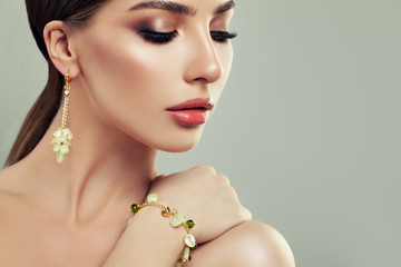 Closeup Portrait of Young Woman with Jewelry. Female Face with Makeup, Gold Bracelet and Earrings...
