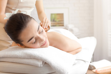 Fototapeta na wymiar Young woman having body scrubbing procedure with sea salt in spa salon