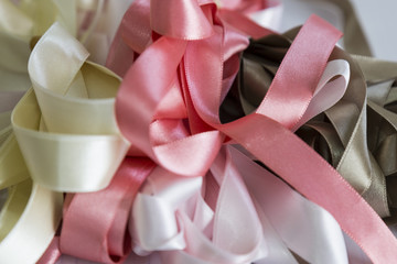 pink,grey and cream color ribbons for textile on the ground.