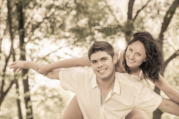 young couple playing in park boyfriend carrying girlfriend on pi
