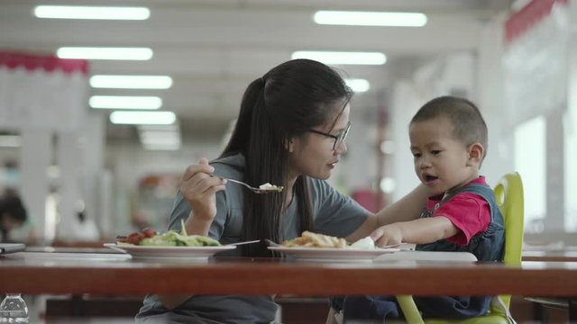 Asian boy about 2 year and 3 months eating food feeded by his mother at cafeteria or canteen