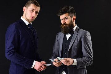 Meeting of reputable businessmen, black background. Man with beard on serious face counting money, pay to partner. Business payment concept. Businessmen, business partners counting profit.