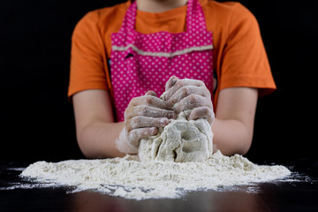 Kneading dough on a black table in a bakery. Baker's hands preparing dough for bread.