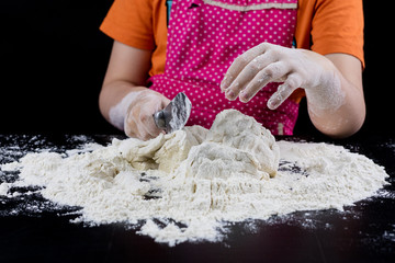 Kneading dough on a black table in a bakery. Baker's hands preparing dough for bread.