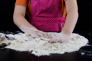 Kneading dough on a black table in a bakery. Baker's hands preparing dough for bread.