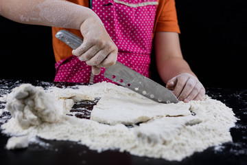 Kneading dough on a black table in a bakery. Baker's hands preparing dough for bread.