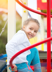 Cute little girl on the playground. Outdoor portrait of five years old girl looking at camera and smiling
