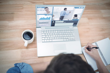 Business interface against hipster writing on spiral notebook by laptop at desk in office