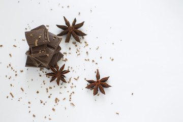 pyramid of chocolate pieces and star anise on white background in centre of picture, sprinkled with chocolate chips with empty space, horizontally