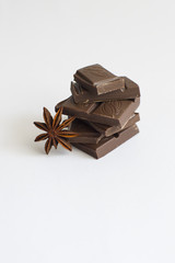 pyramid of chocolate pieces and star anise on white background in centre of picture, vertically