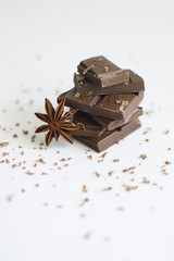 pyramid of chocolate pieces and star anise on white background in centre of picture, sprinkled with chocolate chips, vertically