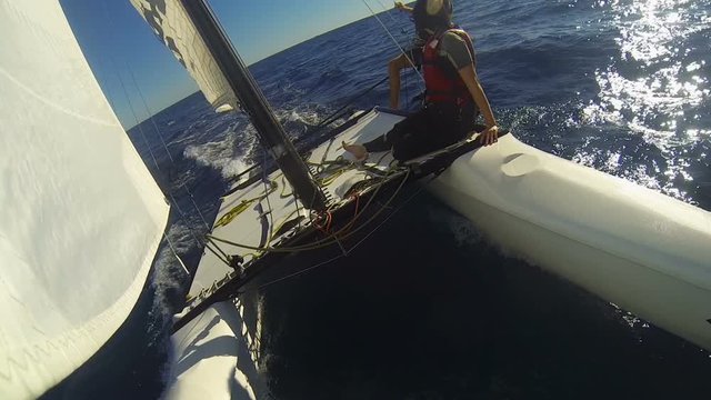 Windsurf catamaran going rapidly in ocean with two people on edge, extreme