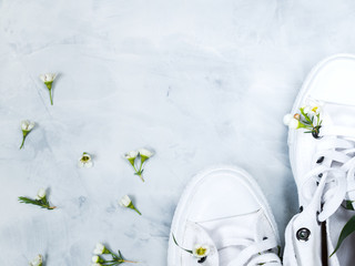 White gumshoes with fresh flowers on grey background