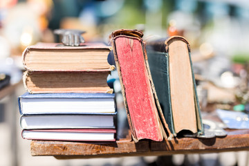 Old aged books at flea market. Vintage retro literature on wooden table outdoors. Street swap meet...