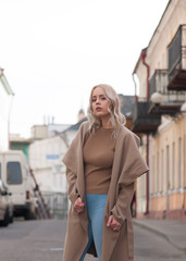 Blonde girl in the coat posing outside