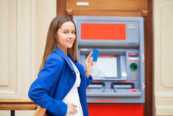 Fototapeta na wymiar Young woman inserting a credit card to ATM