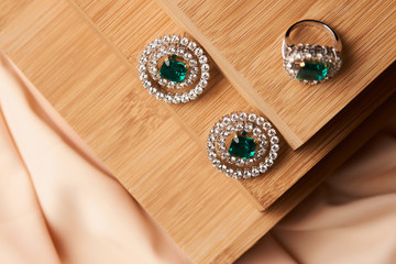 Fototapeta na wymiar Emerald ring and pair of diamond earrings in gold, wedding jewelry with luxury gift box , close-up. Selective focus