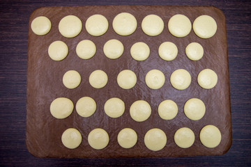 cooking, baking, confectionery and people concept - chef with macarons on oven tray at bakery kitchen