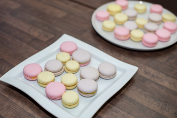 Colorful French or Italian macarons stack on white plate put on wood table with copy space for background.