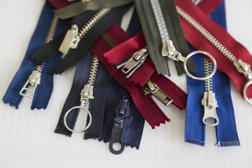 metal and plastic threaded green,blue,grey,red and black zippers on the white background for textile concept. 